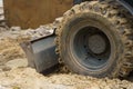 Close-up of dirty bucket teeth and excavator wheel.