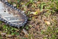 Close up of dirty chainsaw chain placed on ground on grass