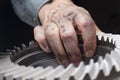 Close-up of a dirty hand of a repairman with a cog wheel in his hand