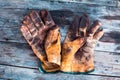 A Close up of a dirty leather work gloves on a wooden table stained with grease and oil Royalty Free Stock Photo