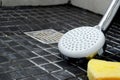 Close up of dirty shower head, cleaning sponge and a spray bottle on the shower floor