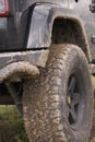 Close up of dirty SUV after driving heavy off-road in wet terrain. Wheels soiled in mud and dirt. Royalty Free Stock Photo