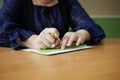 Close-up of disability blind person woman hands writing braille text on paper by using slate and stylus tools making embossed