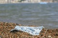 Close-up of a discarded used face mask lies in the surf zone on a sandy pebble beach. Budva, Montenegro Royalty Free Stock Photo