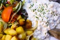 Close up of dish with young salted herring Matjes, white cream sauce with parsley and onions, baked potatoes and fresh salad