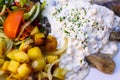 Close up of dish with young salted herring Matjes, white cream sauce with parsley and onions, baked potatoes and fresh salad