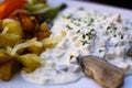 Close up of dish with young salted herring Matjes, white cream sauce with parsley and onions, baked potatoes and fresh salad -