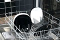 Close-up of a dishwasher with black and white plates on a dark kitchen background Royalty Free Stock Photo