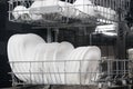 Close-up of the dishwasher compartment filled with large white plates Royalty Free Stock Photo