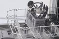 Close-up of a dishwasher container, with cutlery, forks, spoons, knives, after work