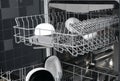 Close-up of dishwasher drawers, with black and white plates on dark kitchen background Royalty Free Stock Photo