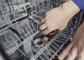 Dishwasher repair. A service center representative diagnoses and repairs a dishwashing machine at home. Specialist in working with Royalty Free Stock Photo