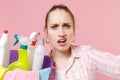 Close up of displeased girl housewife in apron hold basin with detergent bottles washing cleansers doing housework Royalty Free Stock Photo