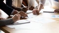 Close up of diverse businesspeople discuss paperwork at meeting