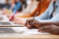 Close-up of diverse hands writing notes during a meeting or classroom session with laptops present Royalty Free Stock Photo