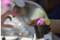 Close-up of diverse Ice-creams pink and yellow colors in Black waffle cones. Hands of the buyer and seller with paper