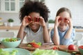 Close up diverse little girls holding red pepper as glasses