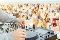 Close up of DJ`s hand playing music at turntable at beach party festival - Crowd people dancing and having fun in club outdoor
