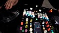 Close up of DJ using a modern sound mixer for playing electro music at the nightclub. Art. Colorful Buttons and vinyl