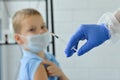 Close-up of a doctor in blue medical gloves with a syringe in his hand, preparing to inject a vaccine to a young boy in a medical Royalty Free Stock Photo
