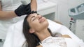 Close-up the doctor cosmetologist in a dressing gown and gloves performs laser procedures on the face of a female