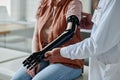 Close up of doctor fitting mechanical prosthetic arm to young woman