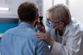 Close up of doctor holding otoscope for ear examination with young man