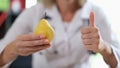 Doctor holding ripe yellow pear in hand and showing thumb up sign Royalty Free Stock Photo