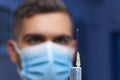 Close-up of doctor with medical mask preparing a syringe for vaccination against covid-19