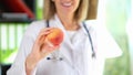 Doctor nutritionist holding ripe peach in hand