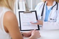 Close up of a doctor and patient hands while phisician pointing into medical history form at clipboard Royalty Free Stock Photo
