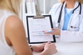 Close up of a doctor and patient hands while phisician pointing into medical history form at clipboard