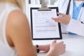 Close up of a doctor and patient hands while phisician pointing into medical history form at clipboard