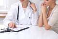 Close up of doctor and patient sitting at the desk while physician pointing into medical form hystory. Medicine a Royalty Free Stock Photo