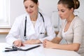 Close up of doctor and patient sitting at the desk while physician pointing into medical form hystory. Medicine a Royalty Free Stock Photo