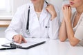 Close up of doctor and patient sitting at the desk while physician pointing into medical form hystory. Medicine a Royalty Free Stock Photo