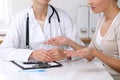 Close up of doctor and patient sitting at the desk while physician pointing into medical form hystory. Medicine a Royalty Free Stock Photo