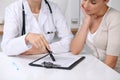 Close up of doctor and patient sitting at the desk while physician pointing into medical form hystory. Medicine a Royalty Free Stock Photo