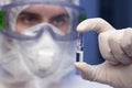 Close-up of doctor with protective clothing holding a ampoule with vaccine in his hand