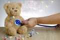 Close-up of doctor`s hand with stethoscope, many colored pills, medicine, capsules, teddy bear kids toy with stick thermometer,