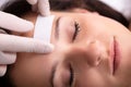 Doctor Waxing Woman`s Forehead