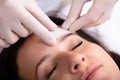 Doctor Waxing Woman`s Forehead