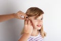 Close up of a Doctor`s hands fitting a hearing aid for a young girl Royalty Free Stock Photo