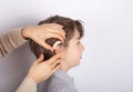 Close up of doctor`s hands inserting hearing aid in a youg boy patient`s ear