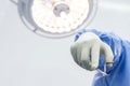 Close up of doctor or surgeon in blue uniform holding medical scissors tool inside an operating room in hospital Royalty Free Stock Photo