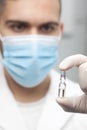 Close-up of doctor with surgical mask holding a ampoule with vaccine in his hand