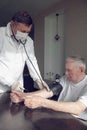 Close-up of a doctor using a stethoscope on an elderly person`s elbow to measure blood pressure. A gerontologist monitors the Royalty Free Stock Photo