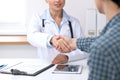 Close up of a doctor woman shaking hands with her male patient. Medicine and trust concept Royalty Free Stock Photo