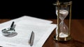 Close-up of document and hourglass on table, contract validity period expiring Royalty Free Stock Photo