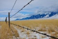 CLOSE UP: Rusty barbed wire fence runs around a meadow under the snowy Rockies